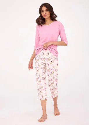 Kobieca piżama damska składająca się z różowej bluzki o długości rękawów 3/4 i dekolcie wykończonym okrągłą lamówką. Bluzka jest wykonana z miękkiej, przyjemnej w dotyku bawełny, która zapewnia komfort noszenia. Spodnie o długości 7/8 są zadrukowane piękn